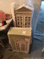 Photo showing two Summer Living hanging cabinets in original packaging, plastic wrapped, and one outside the box for display.