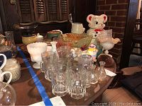 Overview of vintage cookie jar, depression glass bowl and tray, carnival glass dish, vintage glasses, and assorted vintage kitchen collectibles displayed on a table.