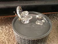 Photo of crystal butterfly and mushroom figurines placed on the lid of a decorative box on carpet.