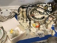 Top view of collection on table showing boxed snowbunnies, several small white figurines, and ceramic village piece with wiring visible.