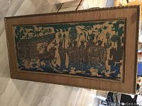 Full view of the framed batik art showing traditional scene with figures and horse chariot