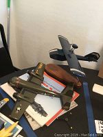 Two model planes shown: green US Army plane missing propeller, and unmarked blue plane on stand, with aviation books underneath.
