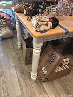 Side view of the wooden table showing one leg and the natural finish on the top surface