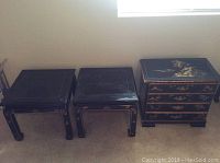 Set of three black lacquer side tables with gold trim arranged side by side, showing the top surfaces and legs