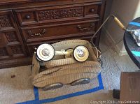 Vintage wicker pram unassembled, showing the main body and metal handle with wooden grip.