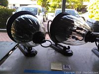 Pair of large Hinkley outdoor wall sconces showing clear ribbed glass shades and metal bases with curved arm mounts.