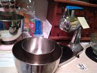 Two stainless steel mixing bowls shown stacked with chrome meat grinder and KitchenAid stand mixer in the background.
