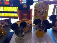 Photo showing Mickey Mouse school bus lunch pail, two Mouseketeer ears hats, two Mickey Mouse gumball machines with Disney graphics