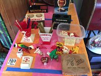 Wide view of the collection showing cup holders, stirring sticks, lighted Corby's parrot pourers, assorted bottle stoppers, and small bar utensils on table