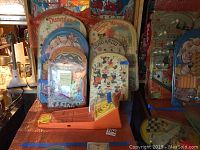 Seven vintage plastic pinball toys displayed vertically, showing varied colorful designs and plastic contours.
