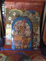 Three vintage Bagatelle pinball marble games, colorful illustrated plastic covered playfields, stacked with pig-themed game in front.