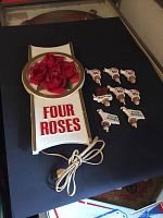 Full view of the Four Roses lighted bar sign placed beside eight Four Roses branded bottle pourers on a dark surface.