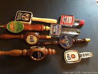 Eight American vintage beer tap handles arranged on a flat surface including Miller Genuine Draft, Miller Light (two), Bud Light, Samuel Adams, Strohs, Budweiser, Sierra Nevada
