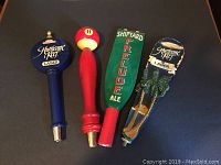 Four vintage beer tap handles from Florida breweries, showing Hurricane Reef, Shipyard, and red pool cue handles.
