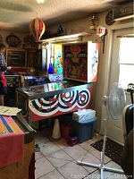 Full side view of cabinet showing red, white and blue musical note swirl pattern, metal legs and surrounding room
