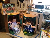 Four Cabbage Patch Kids dolls with original boxes and papers displayed on table, including the Cornsilk doll visible