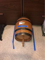 Full view of small wooden cask barrel with metal bands and spigot on wooden stand. Includes inventory tag 130.