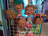 Group shot showing all five vintage spitter faces attached to a wire grid, showing various facial expressions and body fabric details.