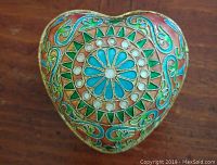 Top view of heart-shaped cloisonne trinket box showing central floral design with turquoise, white, green, and orange enamel patterns.