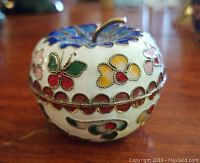 Side view showing butterfly and flower cloisonné designs all around the apple-shaped trinket box with metal rim.