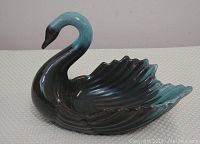 Side view of the Blue Mountain Pottery swan figurine showing the vibrant teal and dark brown glaze with detailed wing feathers.