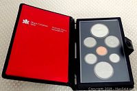 Open red leatherette case showing the seven proof coins in black holder.