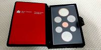 Photo of the opened black presentation case with red inner lining showing the seven Canadian proof coins securely mounted inside.