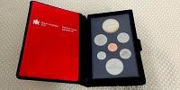 Opened black case with red interior showing seven Canadian proof coins, including a large silver dollar at top and six smaller coins below.