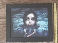 Framed print showing a close-up of the young girl with big eyes and goat in dark background.
