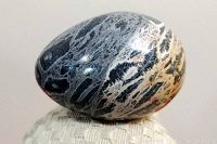 Photo showing polished stone egg with grey and cream natural swirl patterns, highlighting surface texture and shape