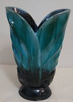 Full view of Blue Mountain Pottery vase showing blue-green and black glaze with leaf relief design and V-shaped opening.