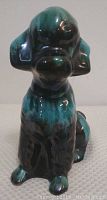 Front view of turquoise and dark green glazed ceramic poodle figurine, sitting pose.