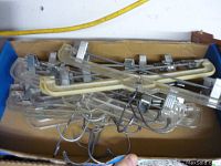 Photo showing multiple clear plastic skirt hangers stacked inside a cardboard box, displaying metal clips and hooks.