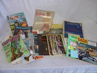Photo of assorted vintage magazines laid out on a flat surface showing various titles and colorful covers including Guns, Shotgun News, and Saga.