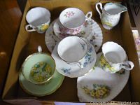 Photo showing top view of vintage Royal Albert cups, saucers, and creamers with floral patterns in various colors such as yellow, pink, and blue.