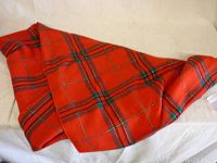 Red tartan patterned table cloth partly folded on a white background showing the overall pattern and condition.