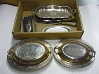 Overview of two large oval silver plated serving trays with integrated handles showing wear and tarnish
