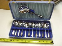 Opened case showing the set of 6 fruit forks, 6 fruit spoons, and 1 large slotted serving spoon inside blue velvet case with satin lining.