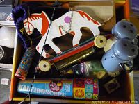 Overview of multiple vintage children's toys including wooden horse pull toy, kaleidoscope, blue shakers, tambourine, and figurines.