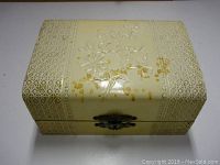 Closed cream-colored vintage jewelry box with floral and geometric embossed patterns.