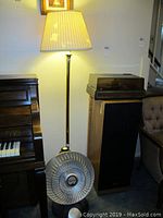 Full view showing the lit floor lamp and the Presto Heat Dish heater placed on the floor adjacent to the lamp and a piano.