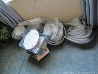 Photo showing a pile of various metal cake pans, some with original stickers and a blue plastic bin that contains cake decorating supplies and a fondant imprint mat.