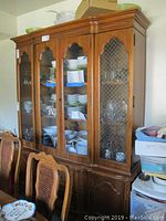 Full front view of the Bassett china cabinet showing wood lattice glass doors, interior dishes, and lower wood cabinets.