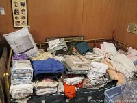 Overview image showing multiple folded linens on a bed with various colors and materials, including some still in packaging.