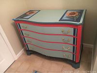 Full view of vintage hand painted dresser with four curved drawers, brass handles, and colorful finish.