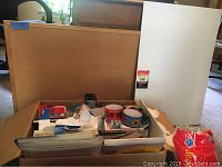 Overview of cork board, foam board, and multiple office supplies including tape rolls and mailing labels in a box