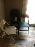 Photo showing 3 folding chairs, 2 leather-like padded chairs and 1 metal chair, arranged in corner.