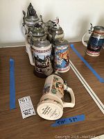 Photo showing several Anheuser Busch Heritage Series ceramic beer steins with metal lids and detailed heritage designs including buildings and wildlife.