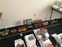 Wide shot showing full train set assembled on short section of track with decanters and accessories in room corner