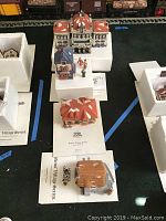 Photo showing multiple miniature village buildings including a large Victoria Station and other Dickens Village series buildings with figures.